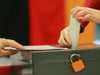 Eine Wählerin wirft ihren Stimmzettel in eine Wahlurne.