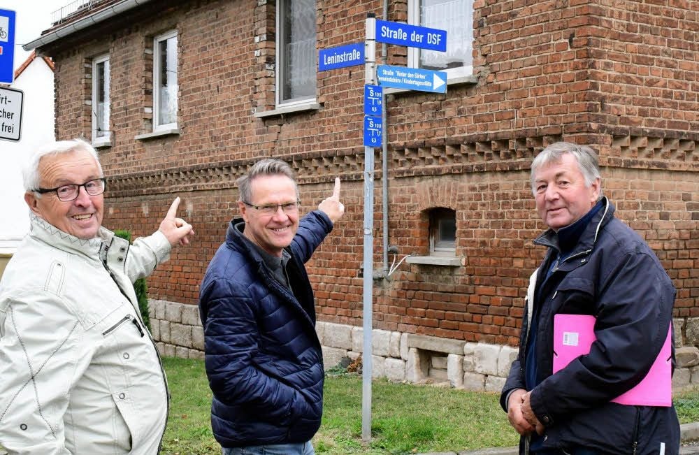 Wolfgang Gotthelf (Mitte) zeigt auf die Straßenschilder mit DDR-Vergangenheit.