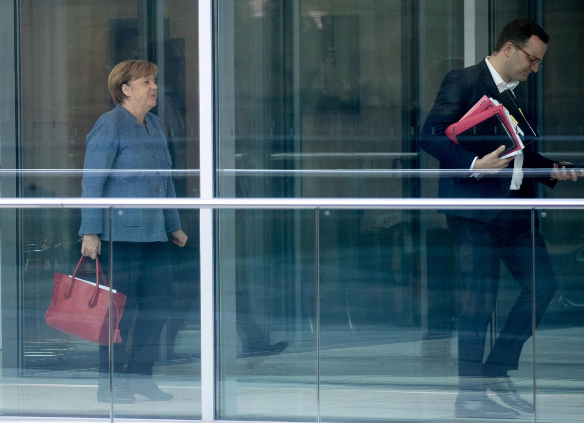 Bundeskanzlerin Angela Merkel (CDU) geht hinter dem CDU-Vizevorsitzenden Jens Spahn (r) im Bundestag in Berlin her.