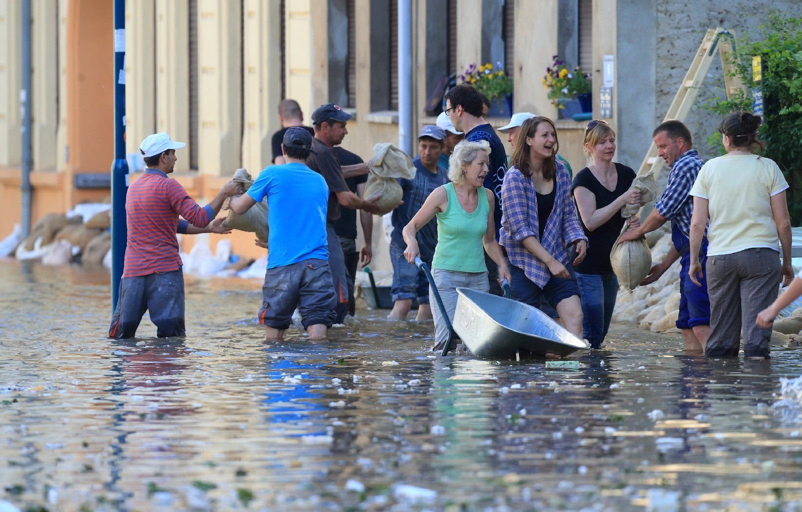 Helfer schichten in einer überfluteten Straße in Magdeburg Sandsäcke gegen das steigende Hochwasser der Elbe zu Dämmen auf.