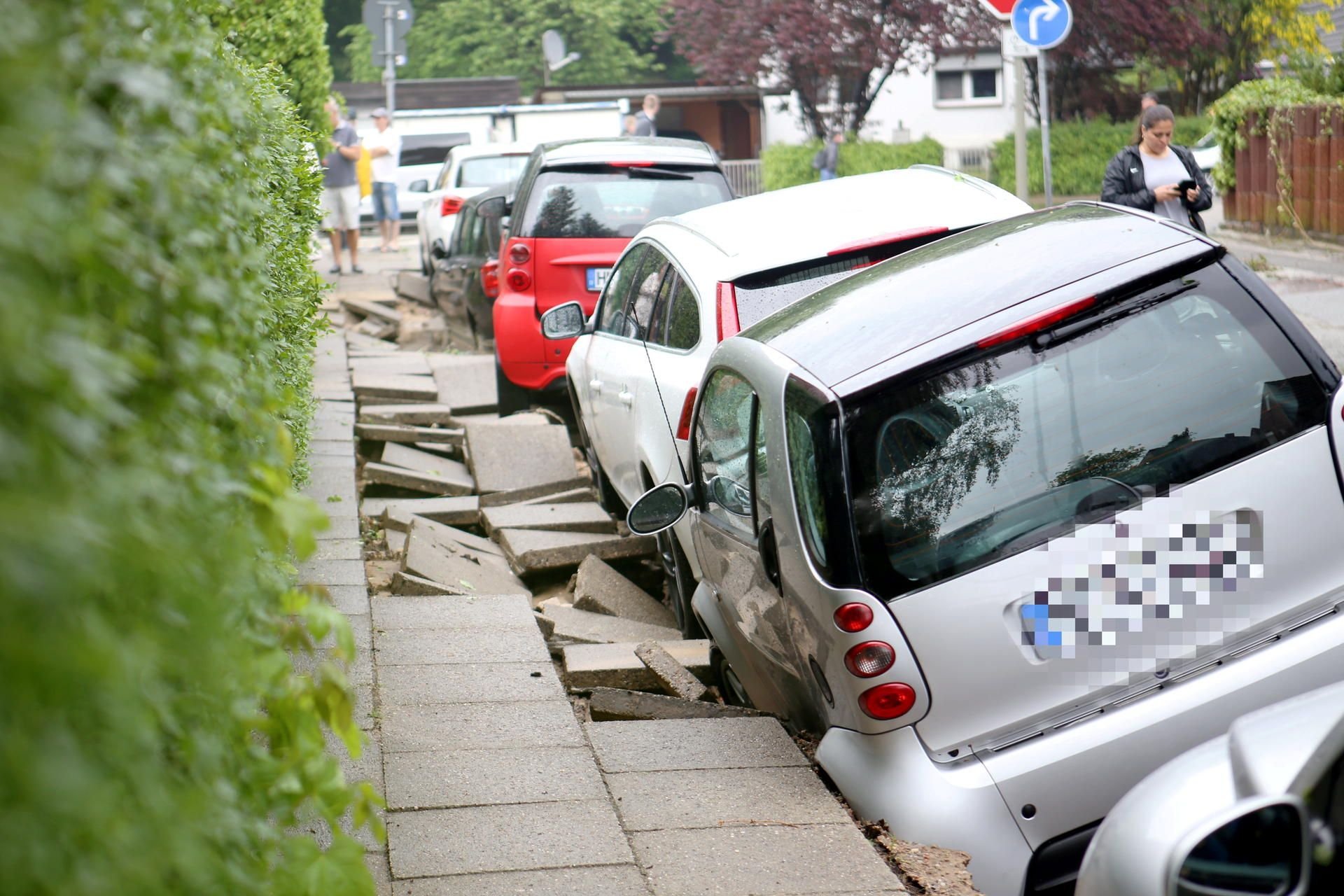 Autos stehen nach einem Unwetter an einer unterspülten Straße in Hamburg-Bergedorf.