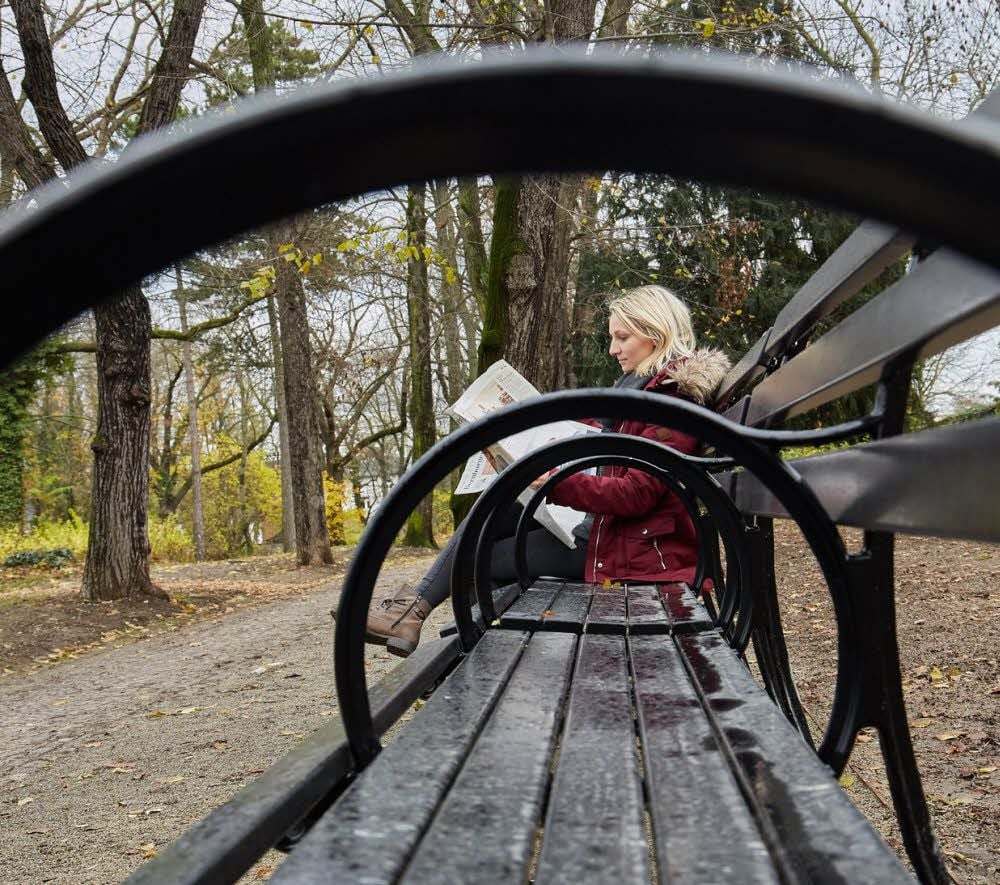 Eine Frau sitzt auf einer Bank im Stadtpark Alte Bibel in Bernburg.
