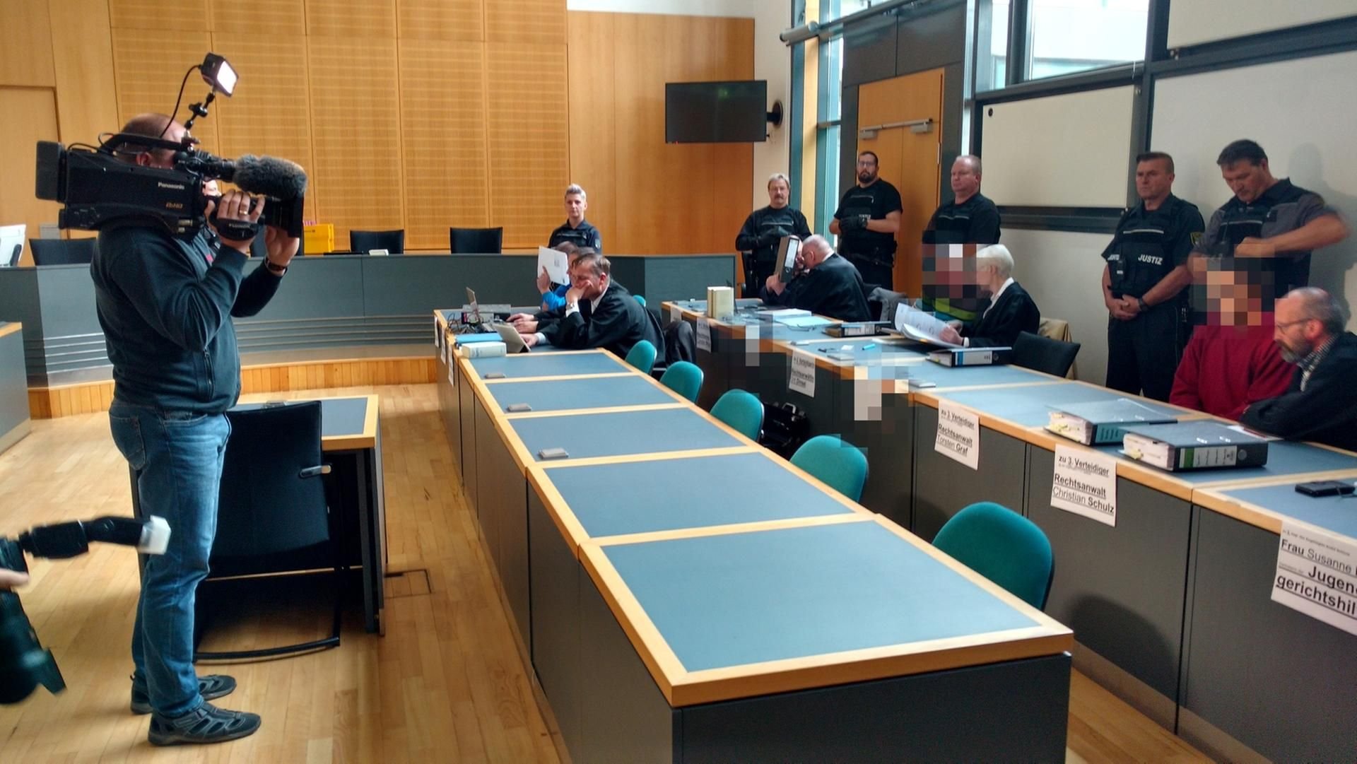 Die vier Angeklagten sitzen neben ihren Rechtsanwälten im Verhandlungssaal des Landgerichtes Magdeburg.