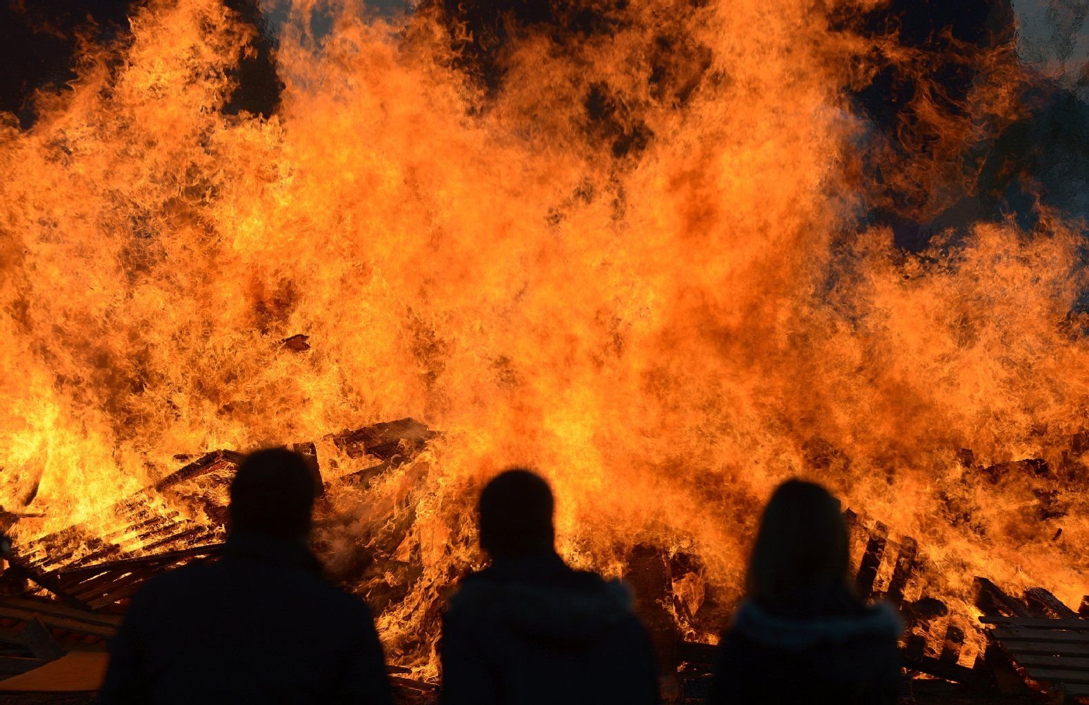 Zuschauer betrachten ein Osterfeuer.
