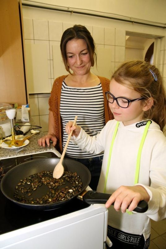 Nancy Martin und Melina (8) rösten die Kürbiskerne für die Suppe.