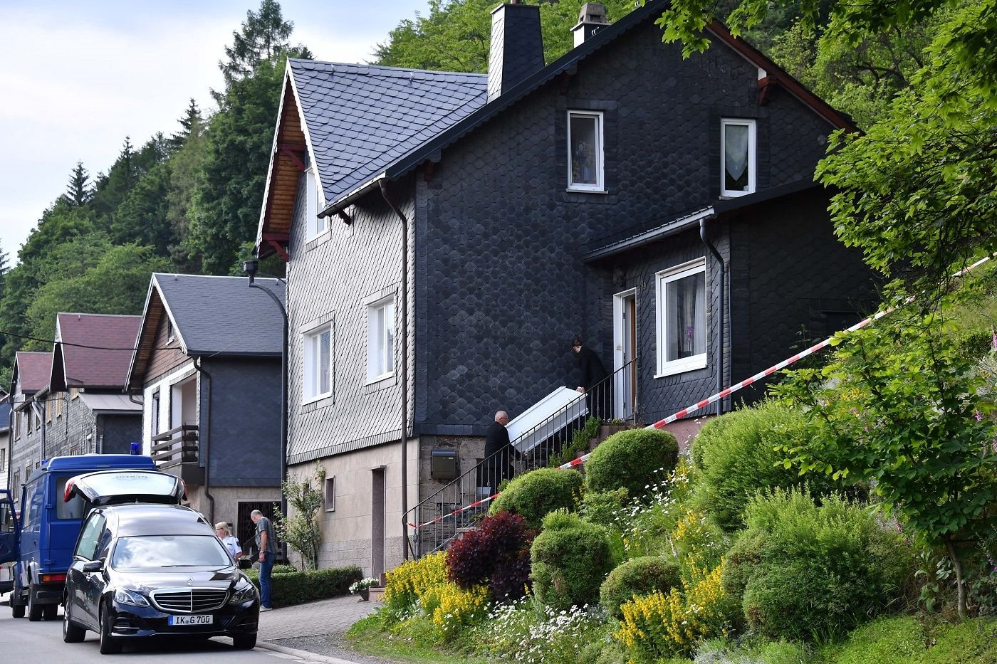 Am Ort des Familiendramas tragen Bestatter einen weißen Sarg für ein Kind aus dem Haus. Dem 28 Jahre alten Familienvater aus Altenfeld (Ilmkreis) wird vorgeworfen, im Juni zwei seiner Söhne mit einem Küchenmesser getötet und einen weiteren Sohn schwer verletzt zu haben.
