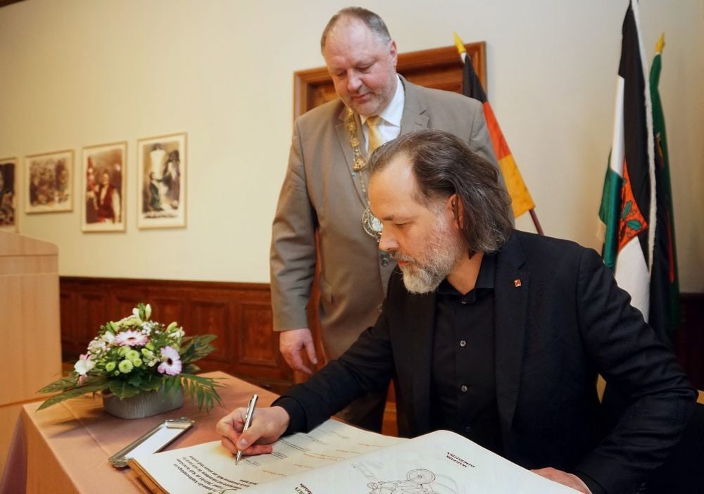 Mike Schubert, Geschäftsführer von Schubert Touristik, trägt sich ins Goldene Buch der Stadt ein.