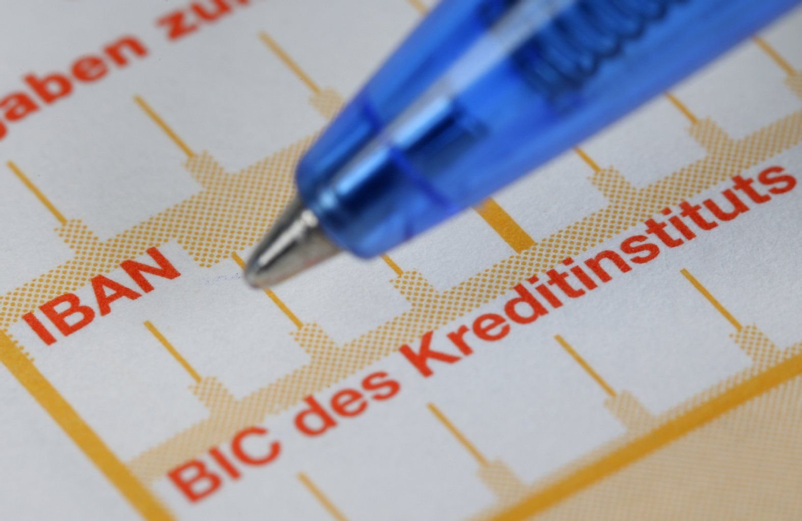 Ein Kugelschreiber ist neben einem Überweisungsträger mit den Schriftzügen "IBAN" und "BIC" zu sehen.