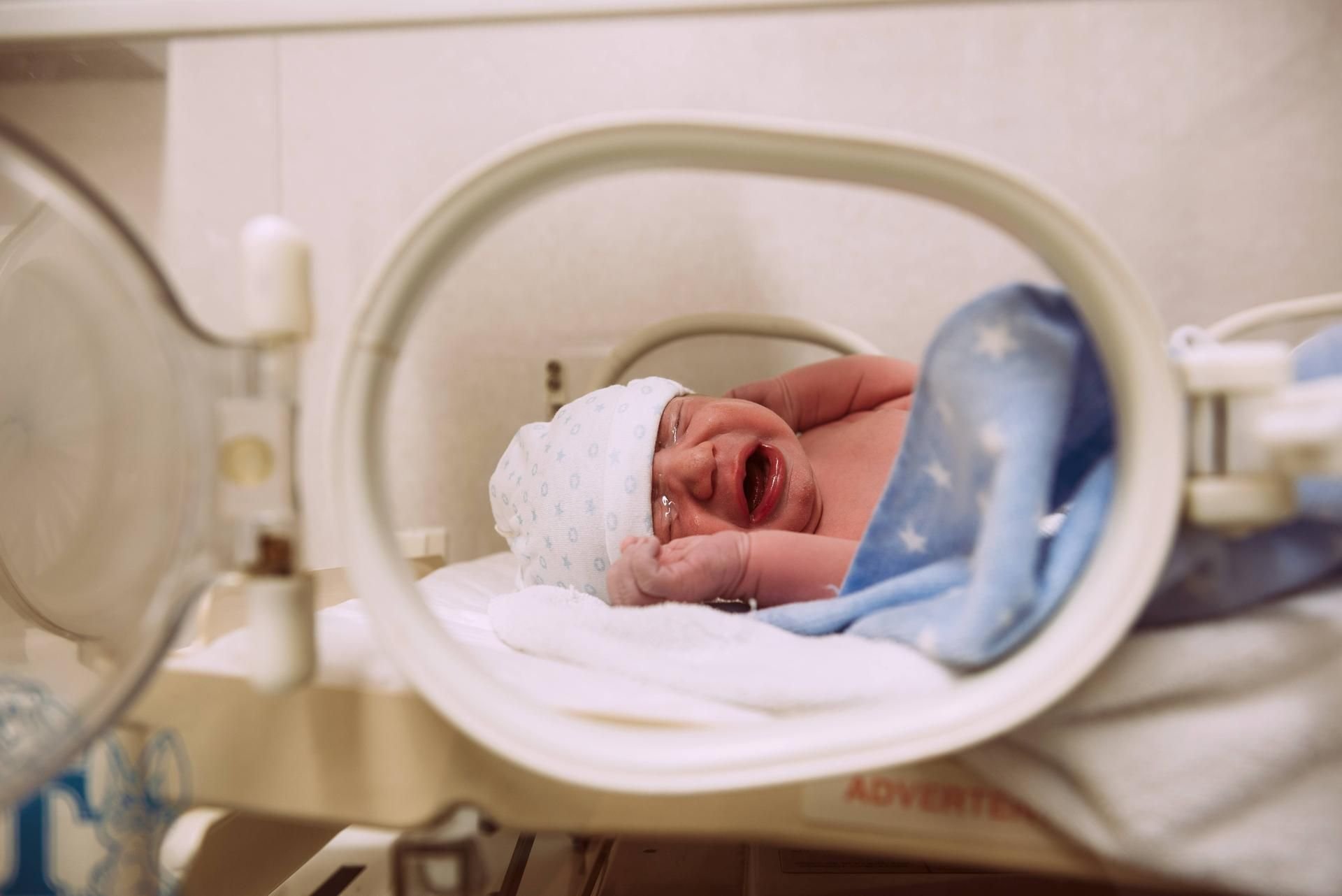 Ein neugeborenes Baby liegt im Inkubator.