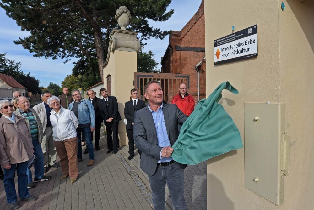 Andre Könnecke enthüllt das Schild am Eingang des Friedhofs.