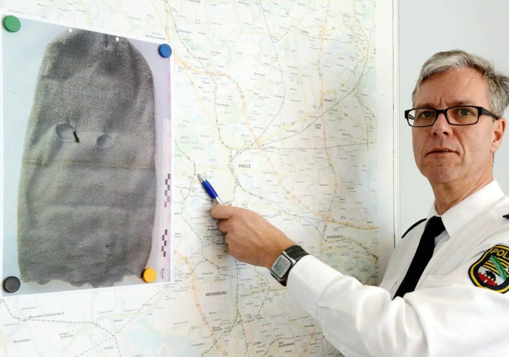 Polizeisprecher Ralf Karlstedt zeigt ein Foto der Maske, die an einem Tatort gefunden wurde.