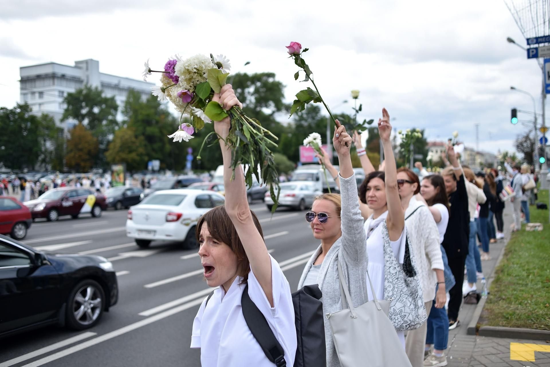 Frauen bilden am Donnerstag mit Blumen in der Hand im Stadtzentrum von Minsk eine Menschenkette.