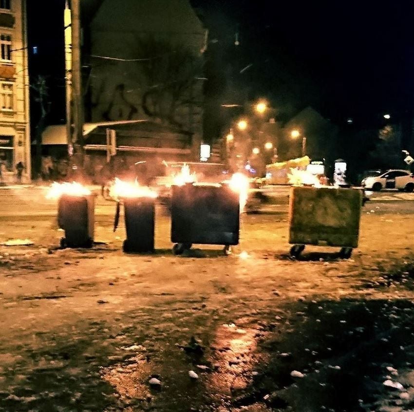 Beim Löschen der Mülltonnen ist die Feuerwehr laut Aussagen der Feuerwehrgewerkschaft von vermummten Personen mit Steinen, Flaschen und Pyrotechnik beworfen worden.