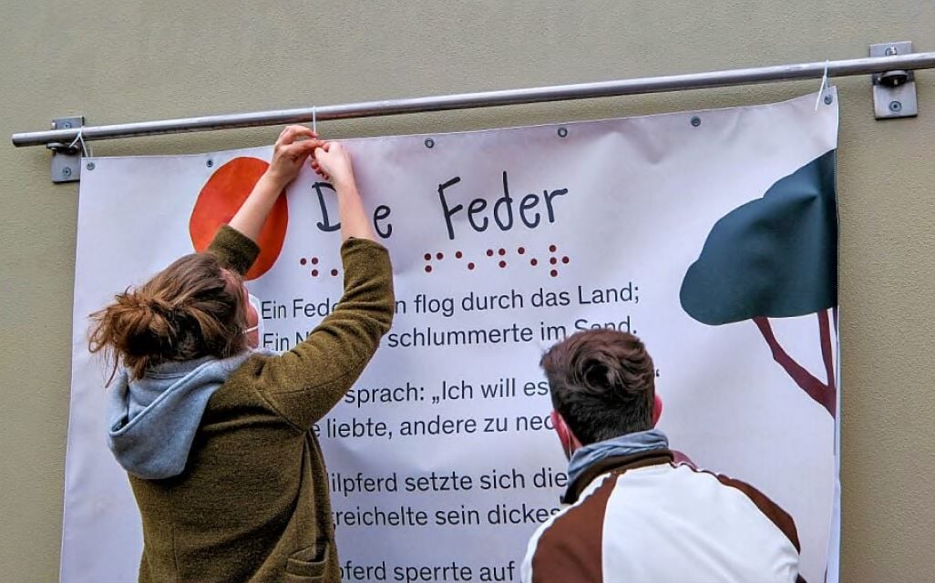 Verena Zimmermann bringt ein von ihr gestaltetes Plakat an.