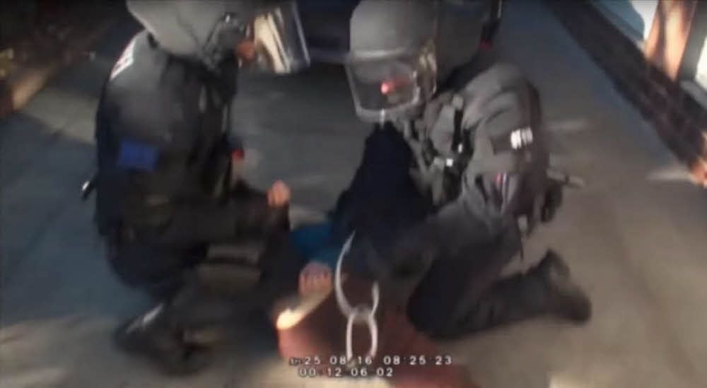 Eine Szene aus dem von Unbekannten ins Netz gestellten Video vom Einsatz am 25. August 2016 in Reuden: Zwei Beamte drücken eine blonde junge Frau zu Boden und fesseln sie mit Kabelbindern.