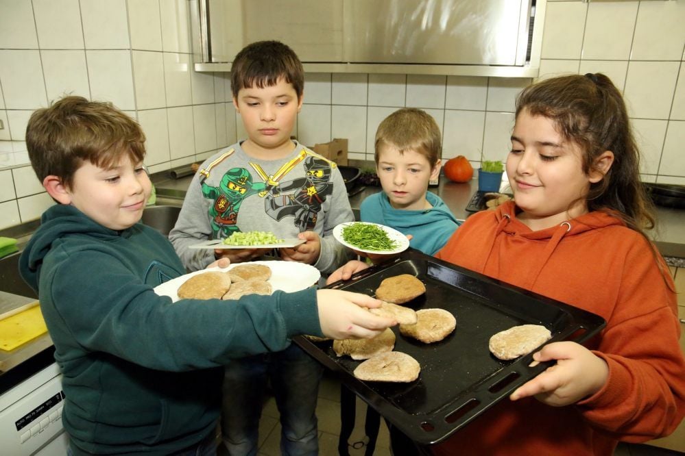 Maxim (v. li.), Danny, Lukas und Renad haben selbst Mehl gemahlen und daraus Brot gebacken. Anschließend servieren es mit Butter und Schnittlauch.