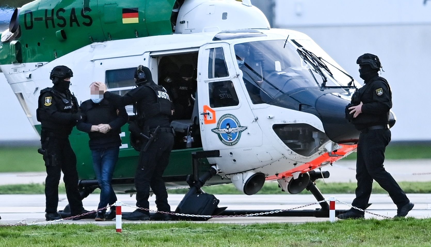 Der angeklagte Stephan B. (2.v.l.) steigt in Begleitung von Justizbeamten am Flugplatz Magdeburg vor Beginn des Prozesstages aus einem Helikopter.