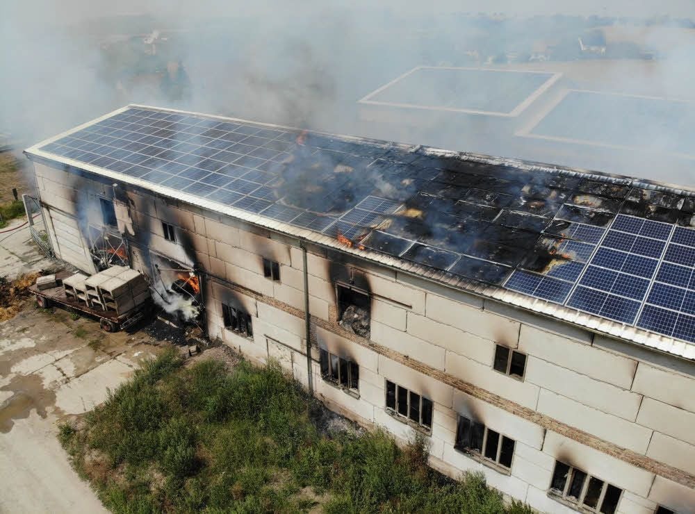 Dieses Drohnenfoto von der Lagerhalle in Gröst vom Sonntag zeigt, wie sich das Feuer schon durch das Dach frisst.