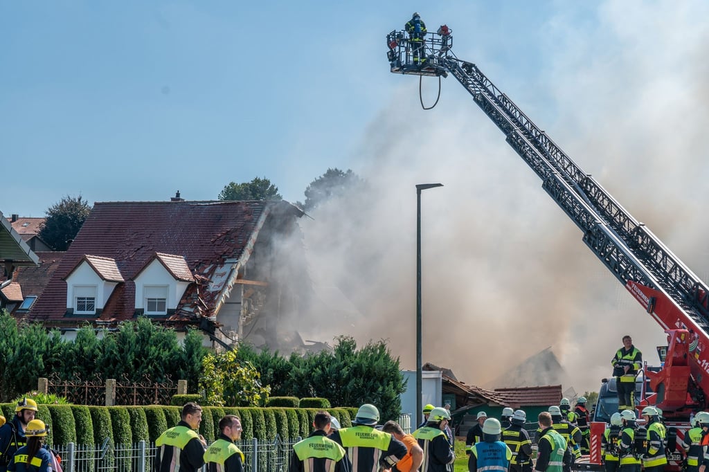 Einsatzkräfte der Feuerwehr sind in der Nähe eines Hauses im Einsatz, in dem es zuvor eine Explosion gegeben hatte.