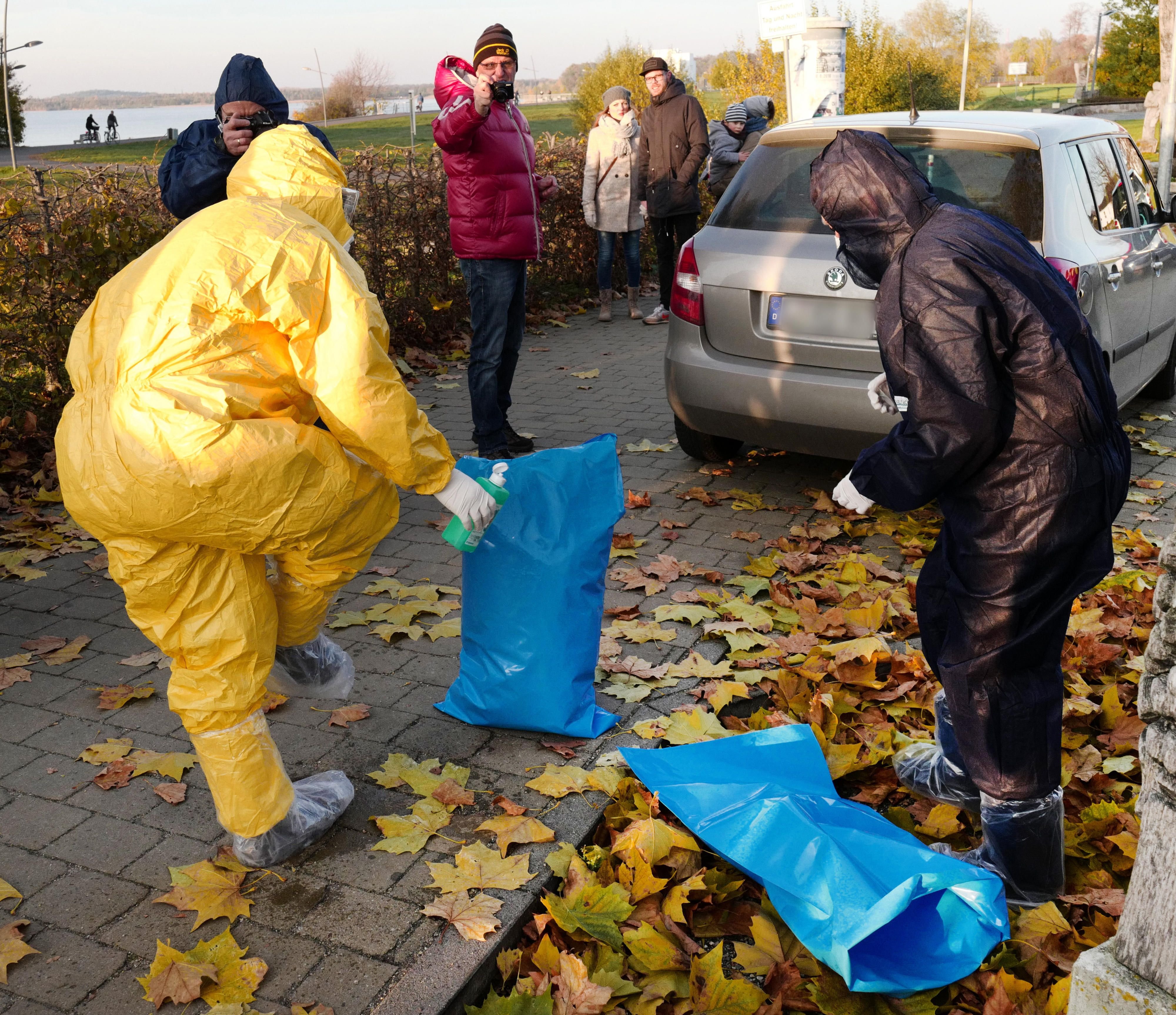 Mitarbeiter des Veterinäramtes ziehen ihre Vollschutzkleidung nach einem weiteren Fund am Cospudener See aus.