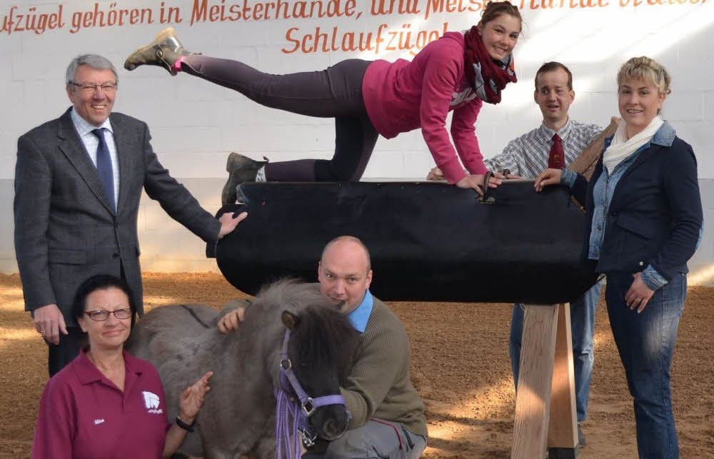 Ein Holzpferd als Ersatz: Lehrling Josephin Apel zeigt eine Voltigier-Figur. Bernd Skrypek (l.) und Spenderin Katrin Berle (r.) beim Auftakt der Aktion.
