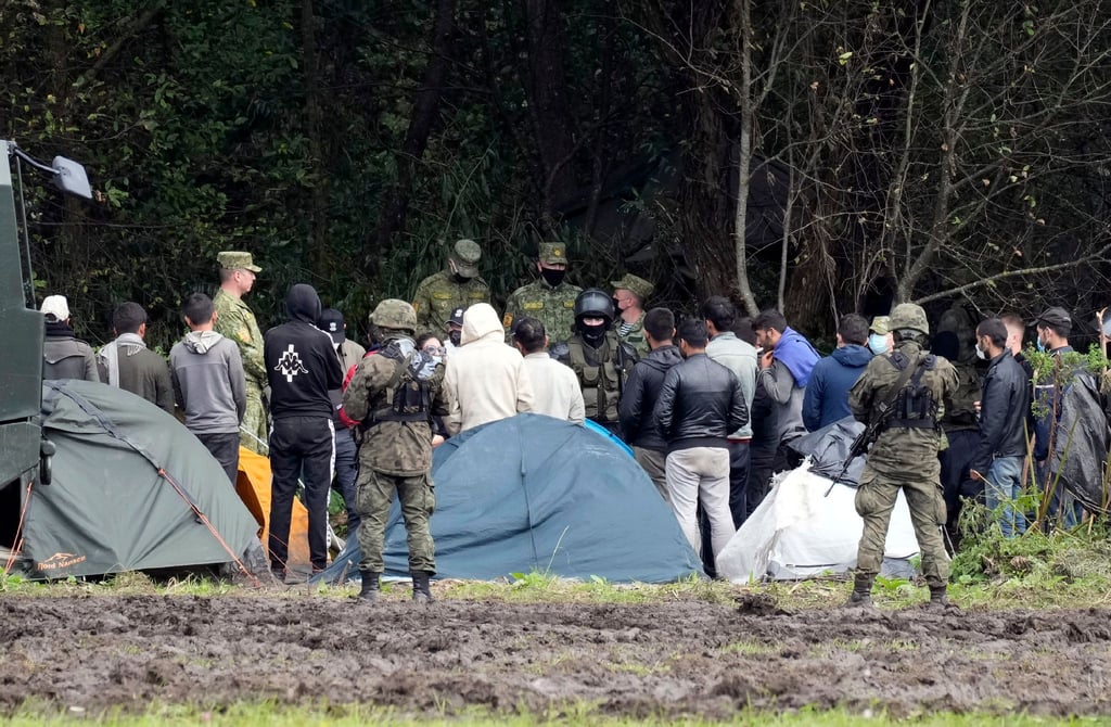 Migranten, die an der Grenze zu Belarus festsitzen, werden von polnischen Beamten umstellt.