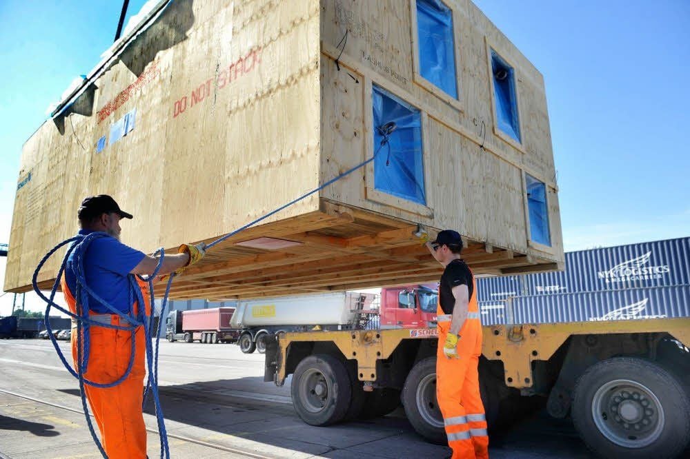 Ein Holzcontainer mit einer tonnenschweren Karosseriepresse wird im Hafen in Aken vom Truck gehoben.