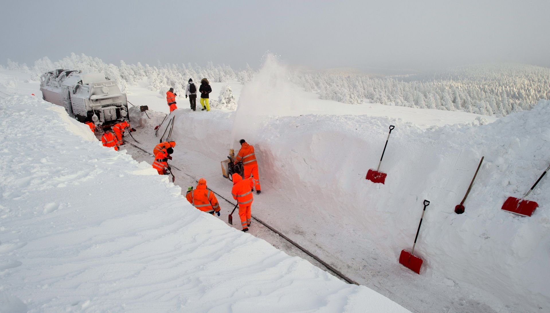 Arbeiter befreien auf dem Brocken, wenige hundert Meter vom Brockenbahnhof entfernt, eine Lokomotive der Brockenbahn aus dem Schnee.