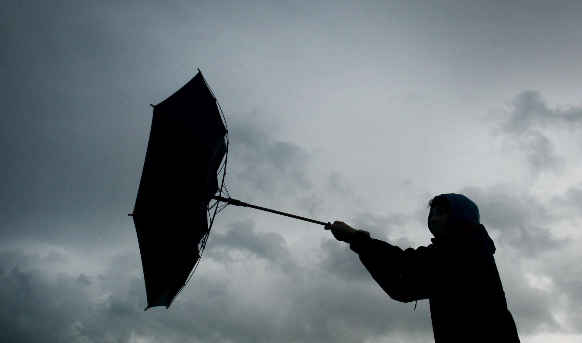 Eine Windböe erfasst den Regenschirm eines Spaziergängers.