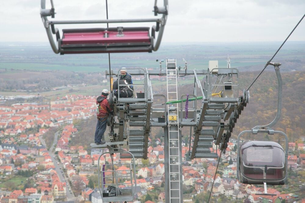 Die Seilbahnen-Mitarbeiter Roland Herdeß, Ralf Kulemann und Holger Zalasa tauschen an einem Stützpfeiler des Sessellifts Rollen aus.