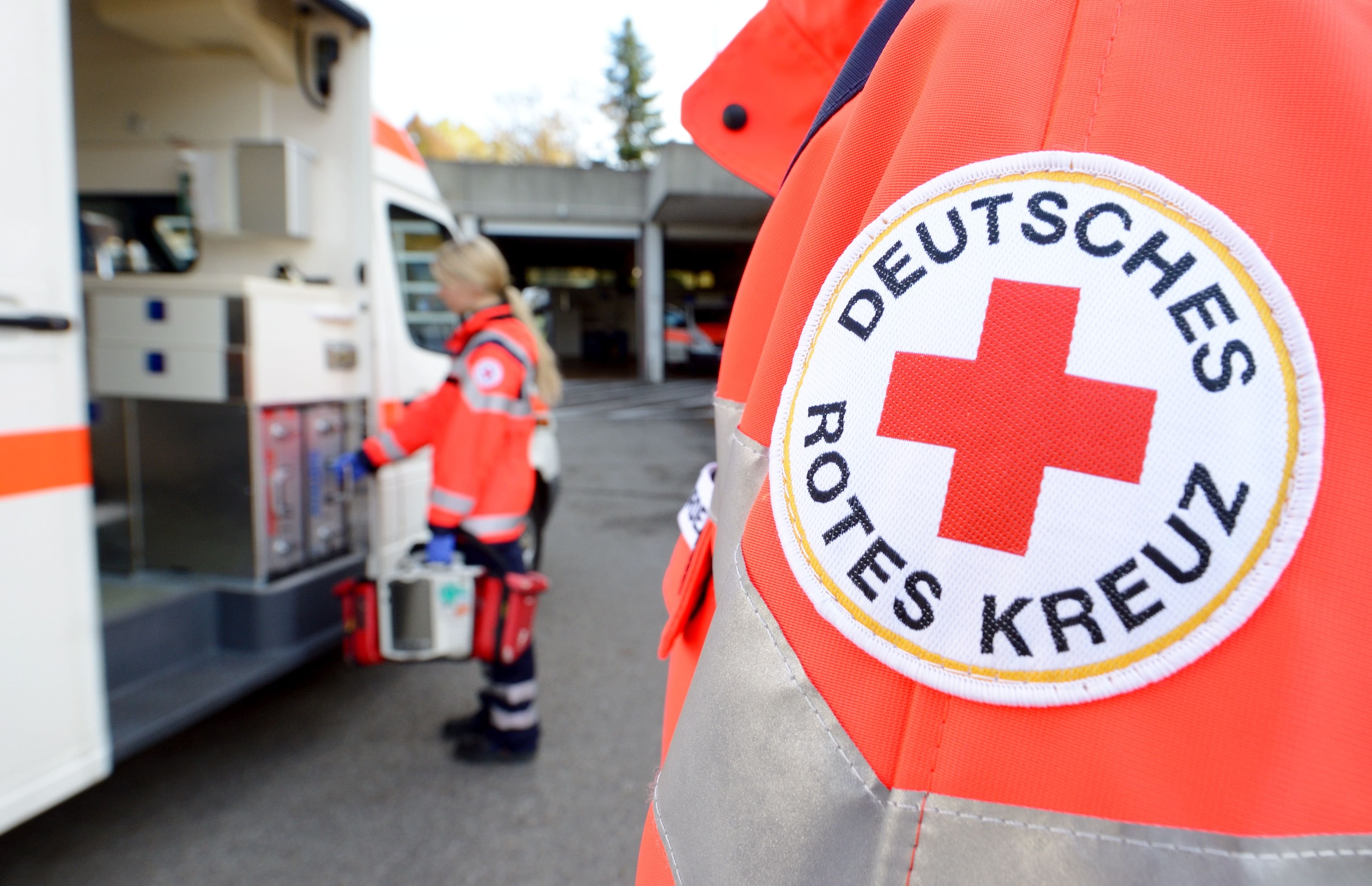 Eine Rettungssanitäterin steht vor einem Rettungswagen des Deutschen Roten Kreuzes.