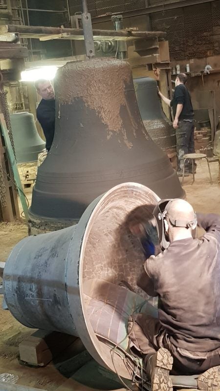 Die Mitarbeiter der Glocken- und Kunstgießerei Rincker haben gut zu tun. Im Hintergrund entstehen Lehmformen; vorn wird die Glocken geputzt.