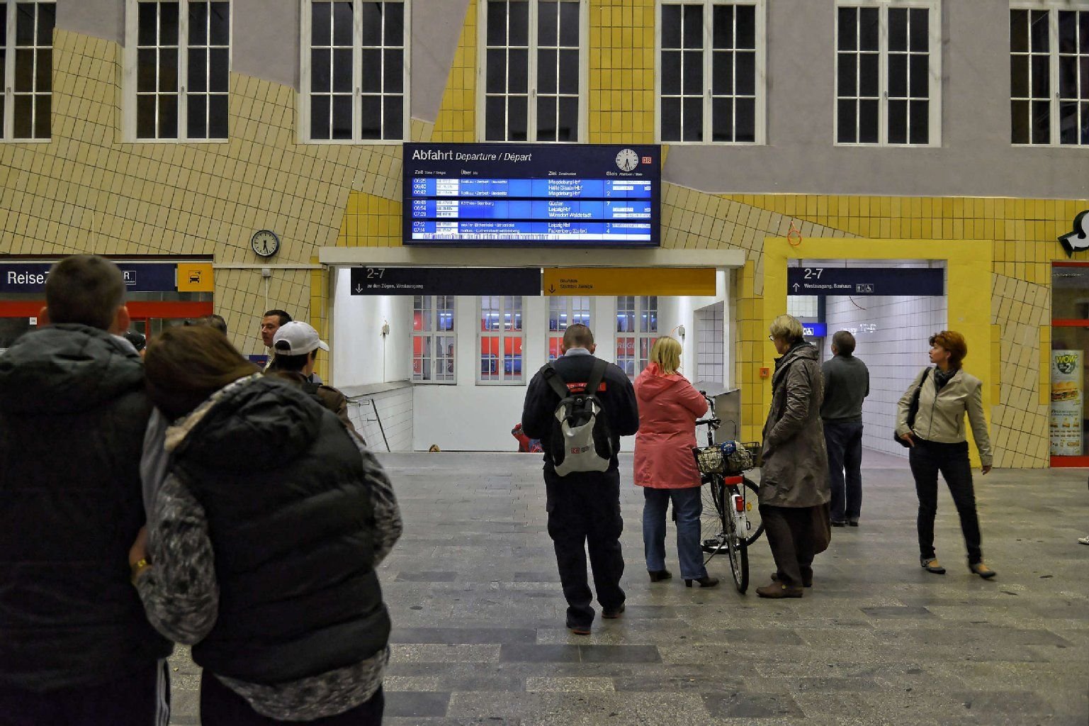 Bahnreisende schauen am Mittwochmorgen auf die Anzeigetafel im Bahnhof Dessau.