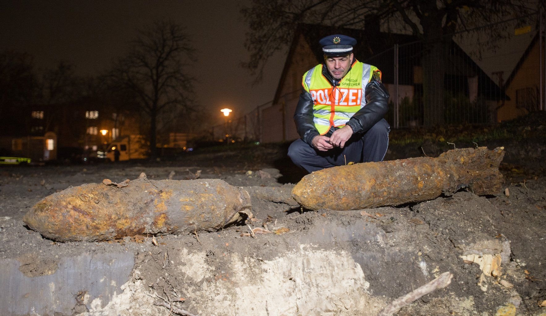 Polizeihauptkommissar Axel Vösterling hockt nahe dem Granatweg in Halle neben zwei Weltkriegsbomben, die dort am 20. November 2014 gefunden worden waren.