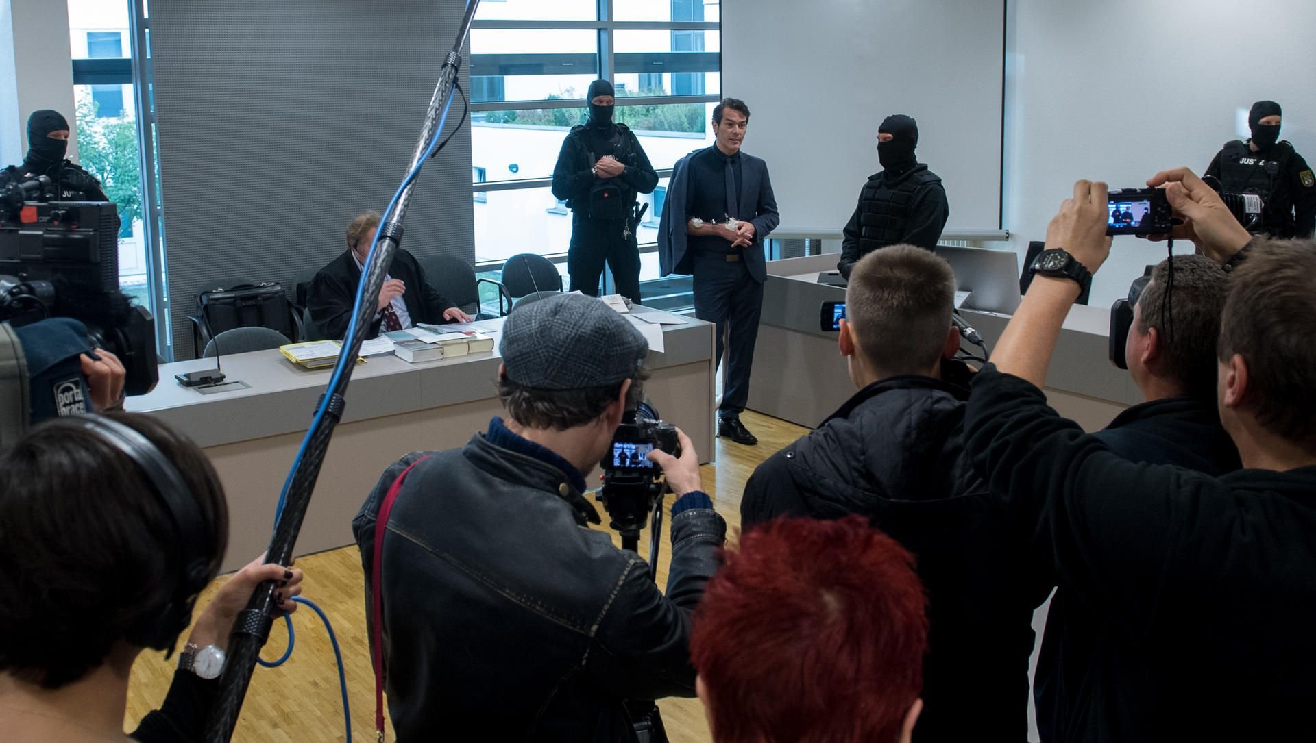 Der ehemalige "Mister Germany" Adrian Ursache (hinten 3.v.r.) spricht im Landgericht in Halle (Saale) vor Prozessbeginn im Gerichtssaal mit Journalisten.