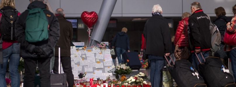 Reisende stehen am Samstag am Flughafen Düsseldorf vor Blumen und Kerzen für die Opfer des Germanwings-Unglücks.