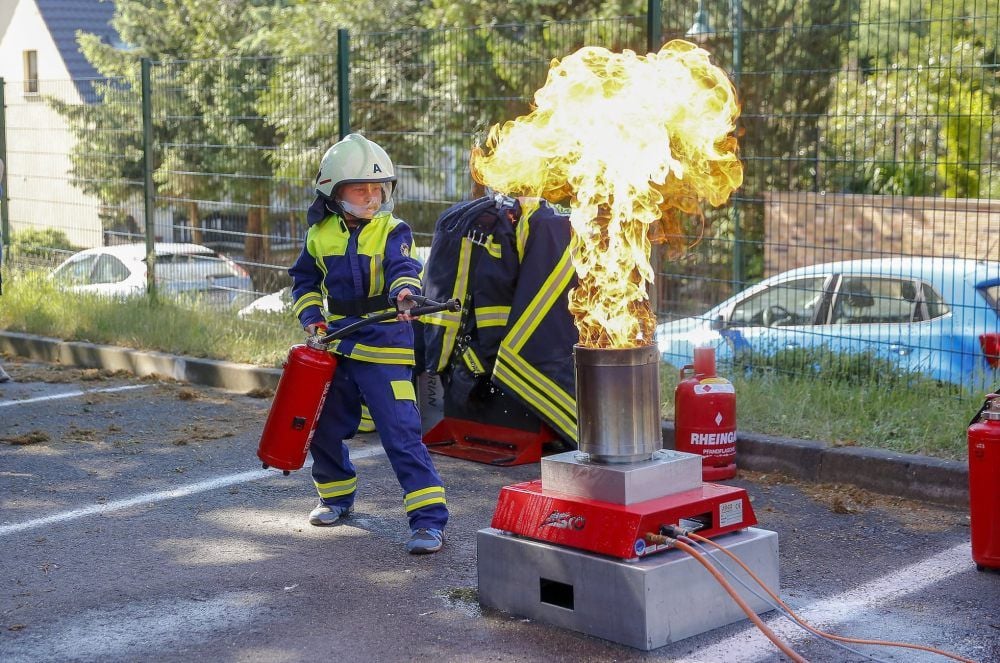 Das Jugendfeuerwehr-Mitglied zeigt den Einsatz eines Feuerlöschers.