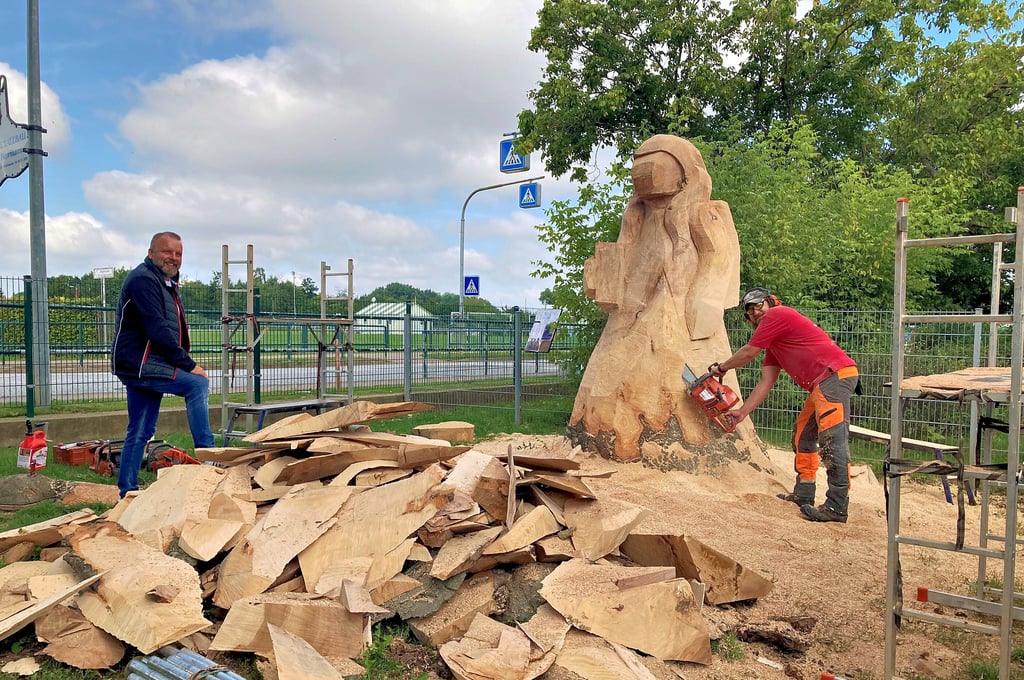 Kettensägenschnitzer Sebastian Seiffert schnitzt an ?Lucy?. So soll die Figur heißen, die er aus einem Baumstamm an der Grundschule Barnstädt herstellt. Finanziert wird das Projekt vom Barnstädter Unternehmen Sören Lorenz (l.).