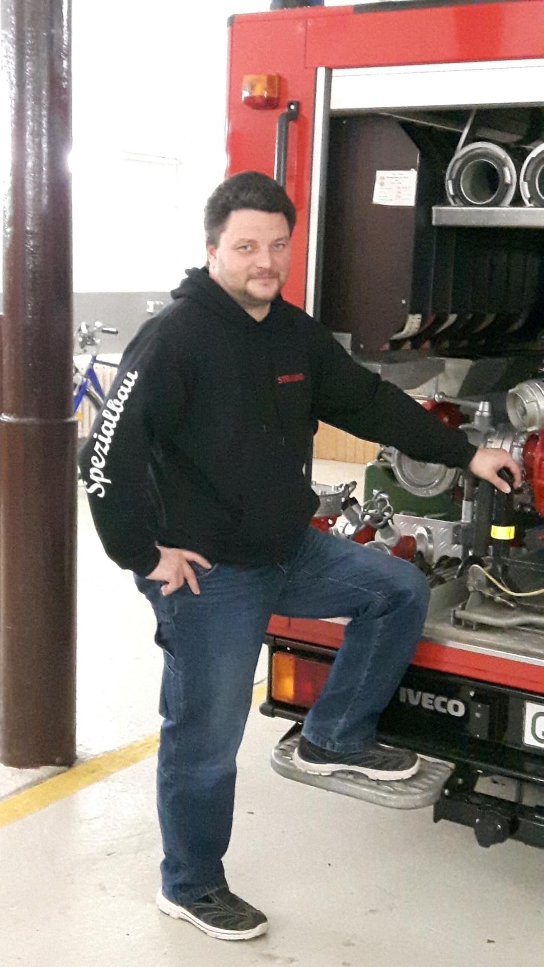 Hardy Noah lässig vor einem der Löschfahrzeuge in der Feuerwache Wedderstedt.