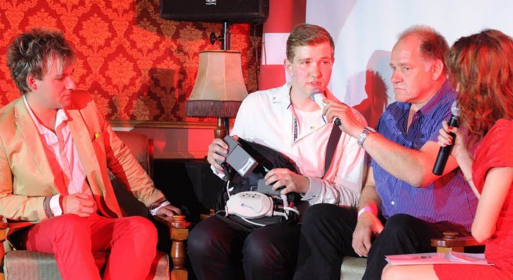 Phil Stewman hört aufmerksam zu, wie Kevin Kerrutt (v.l.) bei der Spenden-Gala in Gerbstedt die Funktion seines künstlichen Herzens erklärt.