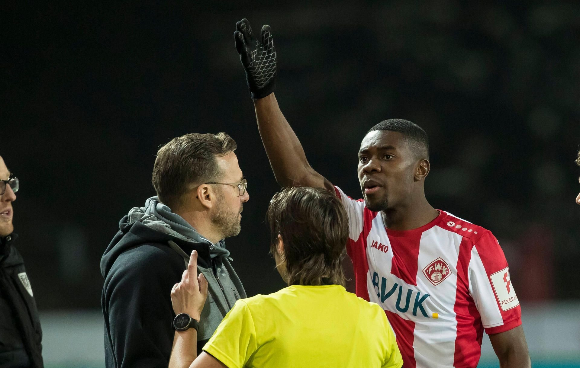 Würzburgs Leroy Kwadaawo (rechts) im Gespräch mit Münsters Trainer Sascha Hildmann und Schiedsrichterin Katrin Rafalski