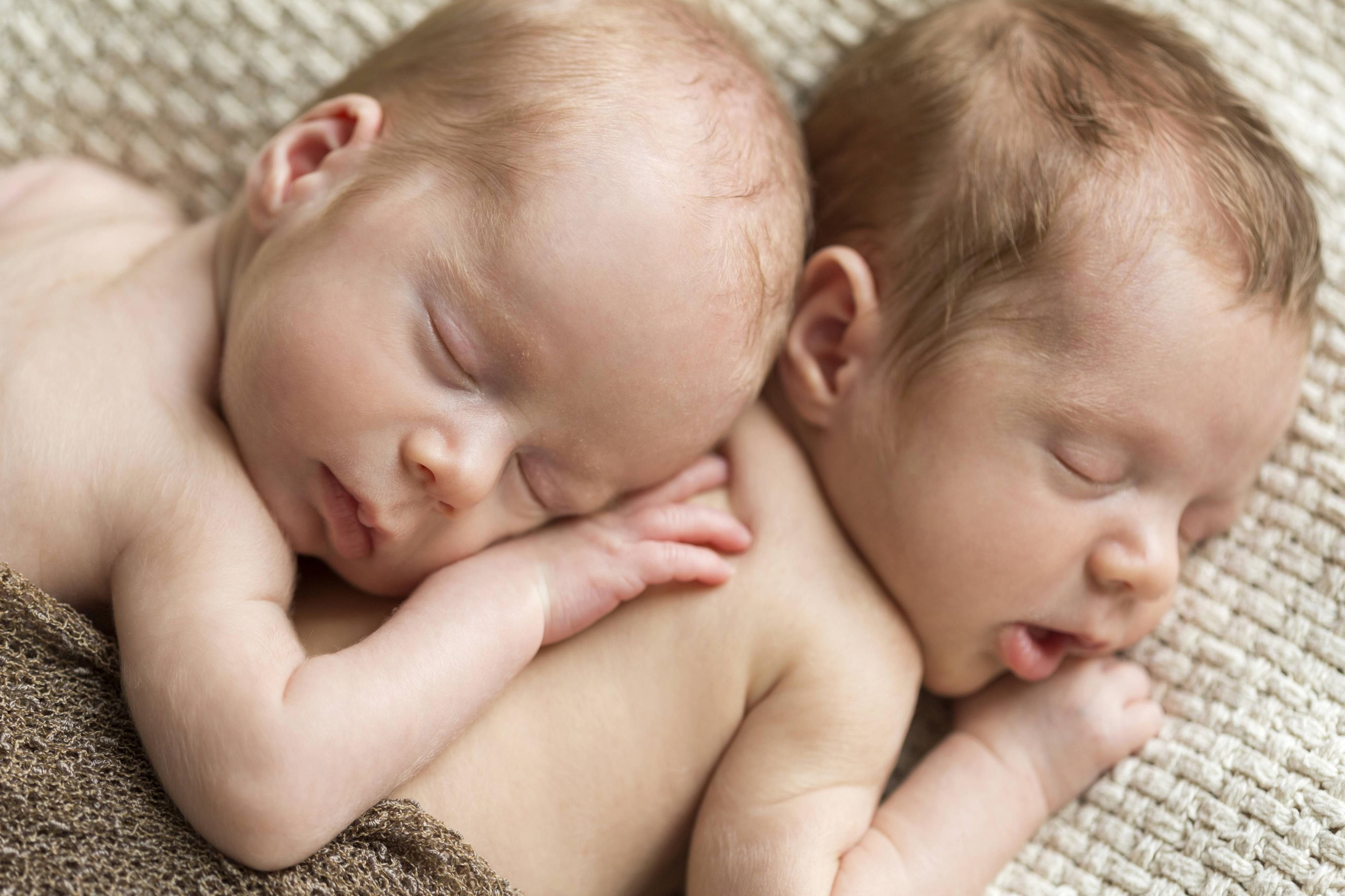 Schlafende Zwillings-Babys kuscheln sich aneinander (Symbolfoto).