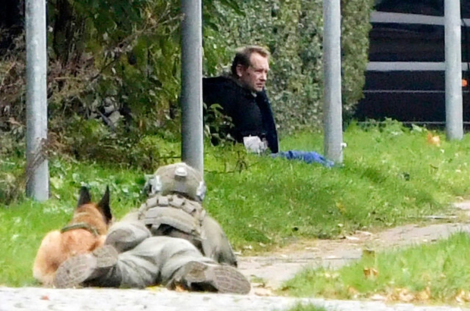 Ein Polizist (l.) liegt neben einem Polizeihund am Boden und beobachtet Peter Madsen.