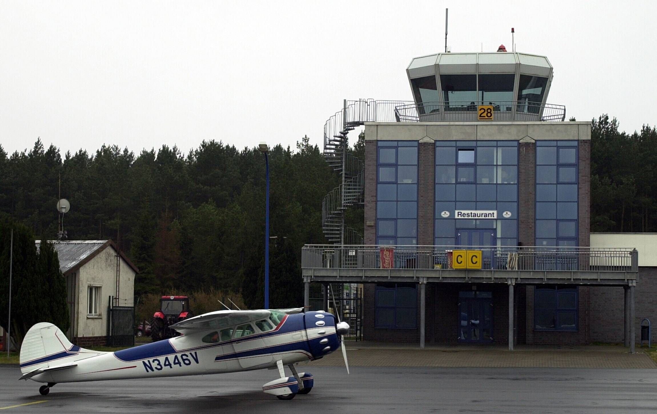 Eine Oldtimer-Cessna steht vor dem Empfangsgebäude mit Tower des Flughafens Heringsdorf/Usedom.