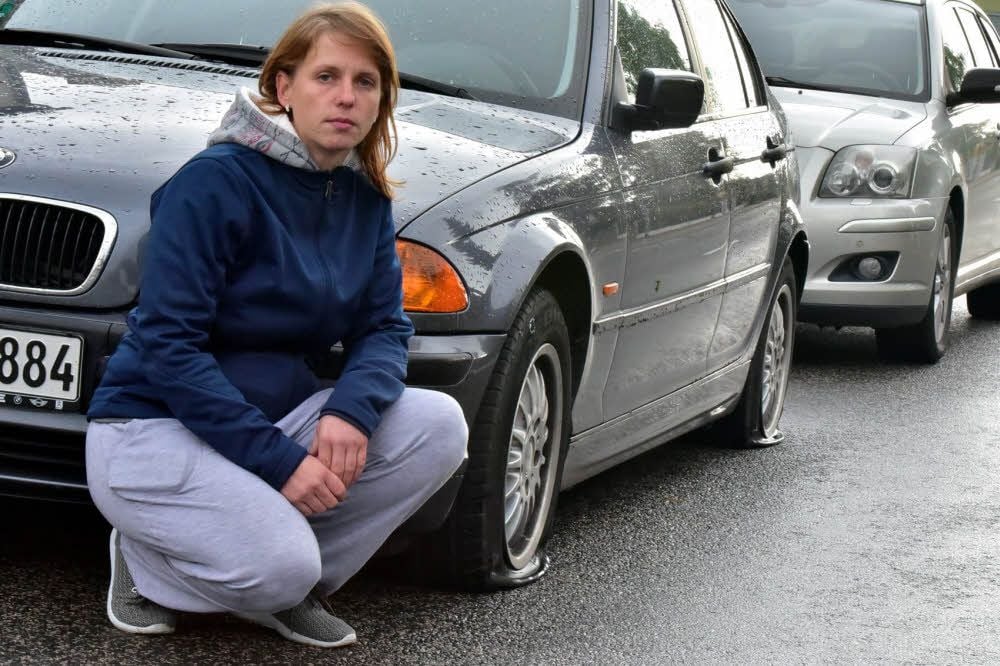 Diana Schmidt hockt vor ihrem Auto, dessen Reifen zerstochen worden sind.