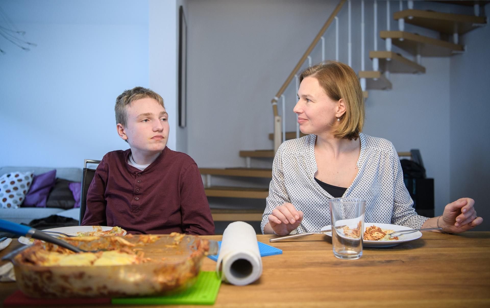 Aron, der frühkindlichen Autismus hat, sitzt neben seiner Mutter Katja.
