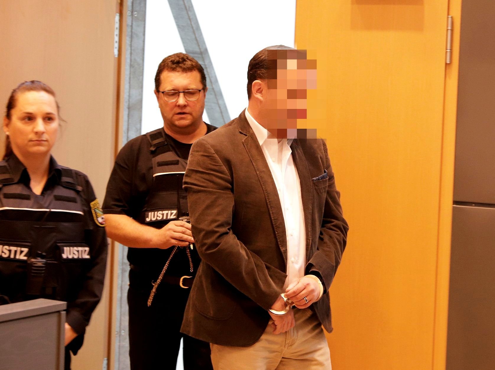 Der ehemalige Chefarzt wird von Justizbeamten in den Verhandlungssaal im Landgericht Magdeburg geführt.