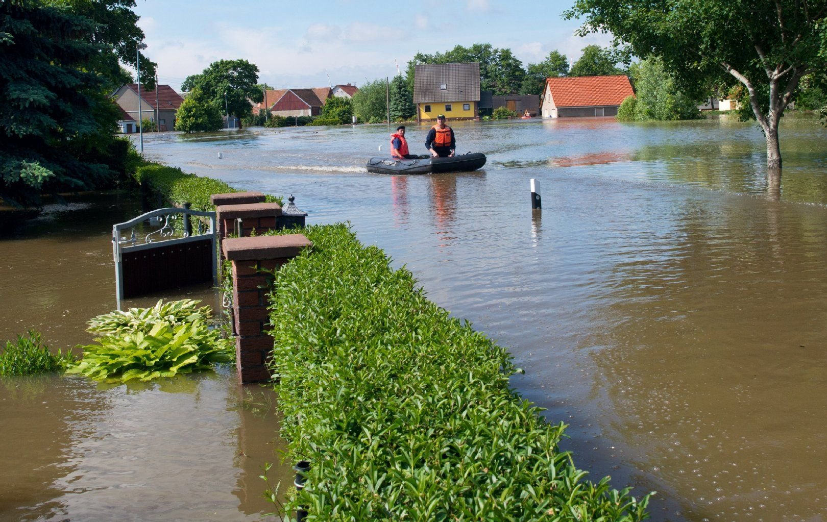 Feuerwehrleute fahren mit einem Schlauchboot über die überflutete Straße in dem kleinen Dorf Kabelitz im Kreis Stendal.