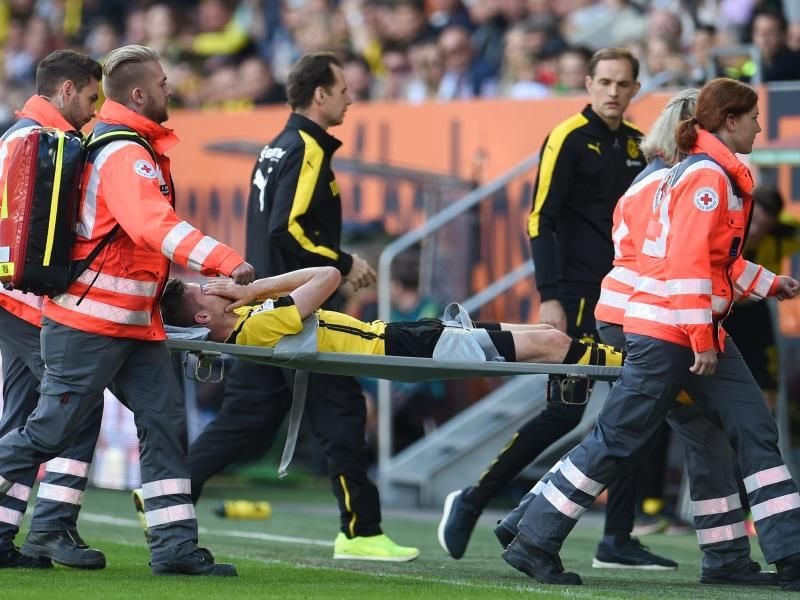 Julian Weigl wird nach seiner Fußverletzung vom Feld getragen. Im Hintergrund BVB-Trainer Thomas Tuchel (2.v.r).