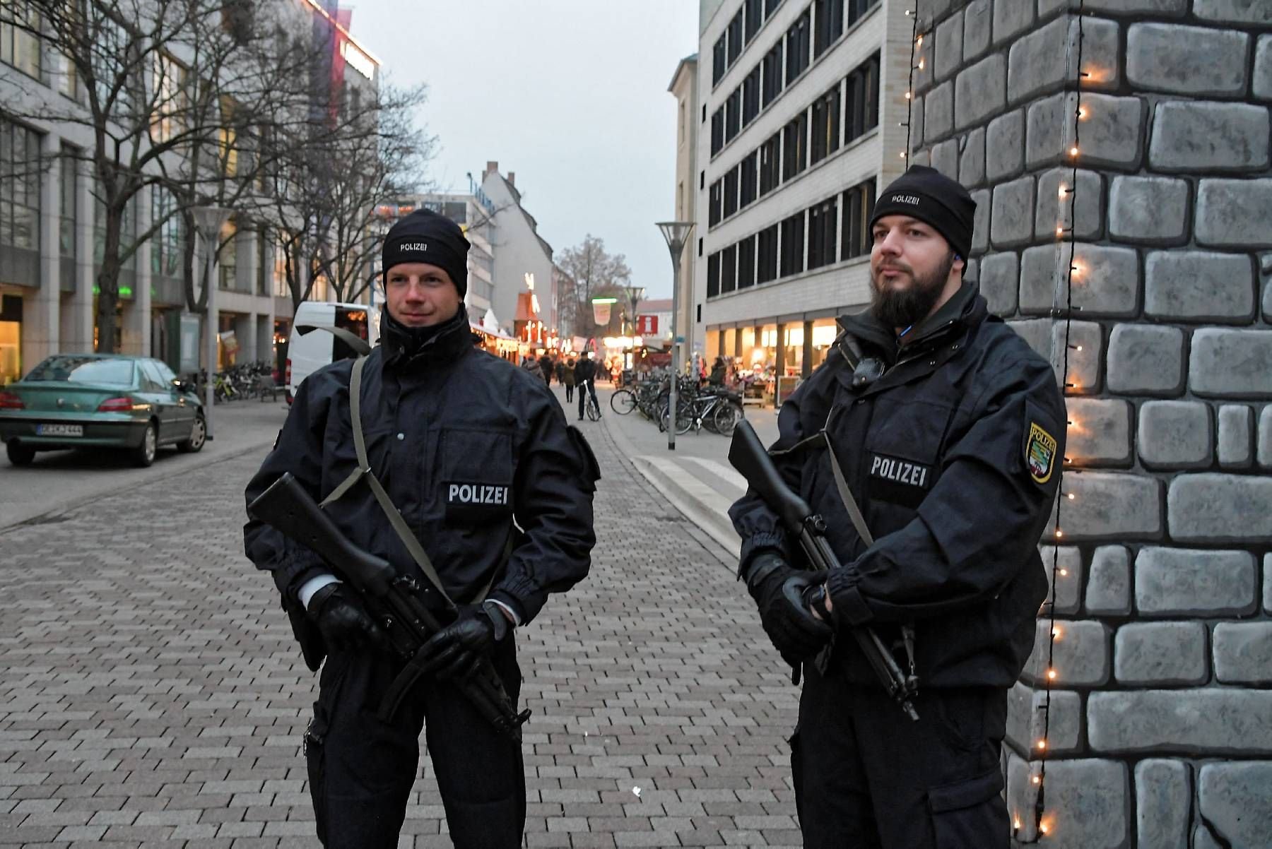 Zwei Polizisten stehen mit Maschinenpistolen nahe der Marienkirche am Weihnachtsmarkt in Dessau.